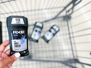 hand holding axe deodorant over shopping cart of axe deodorant