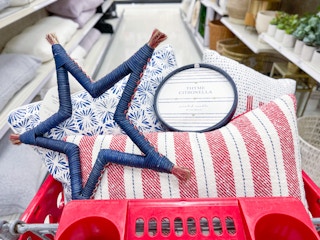 A variety of red white and blue home decor items sitting in the top of a store cart.