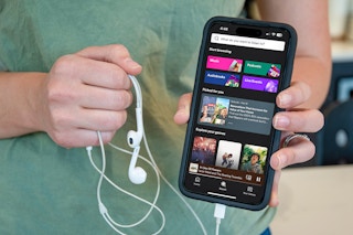 someone holding a smart phone showing the spotify app