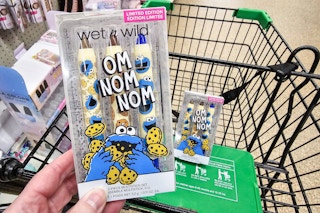person holding sesame street themed makeup collection over a cart