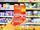 hand holding three boxes of motrin pain relievers in walmart aisle