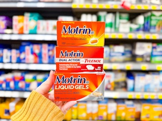 hand holding three boxes of motrin pain relievers in walmart aisle
