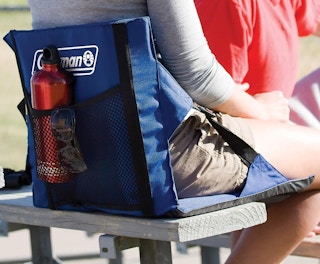 a person sitting on a blue cushion on a stadium bench outside