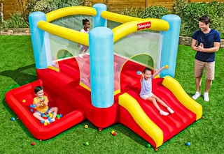 Lifestyle image of the Fisher-Price Bouncemania Inflatable Bounce House being used outdoors (3 children 1 adult)