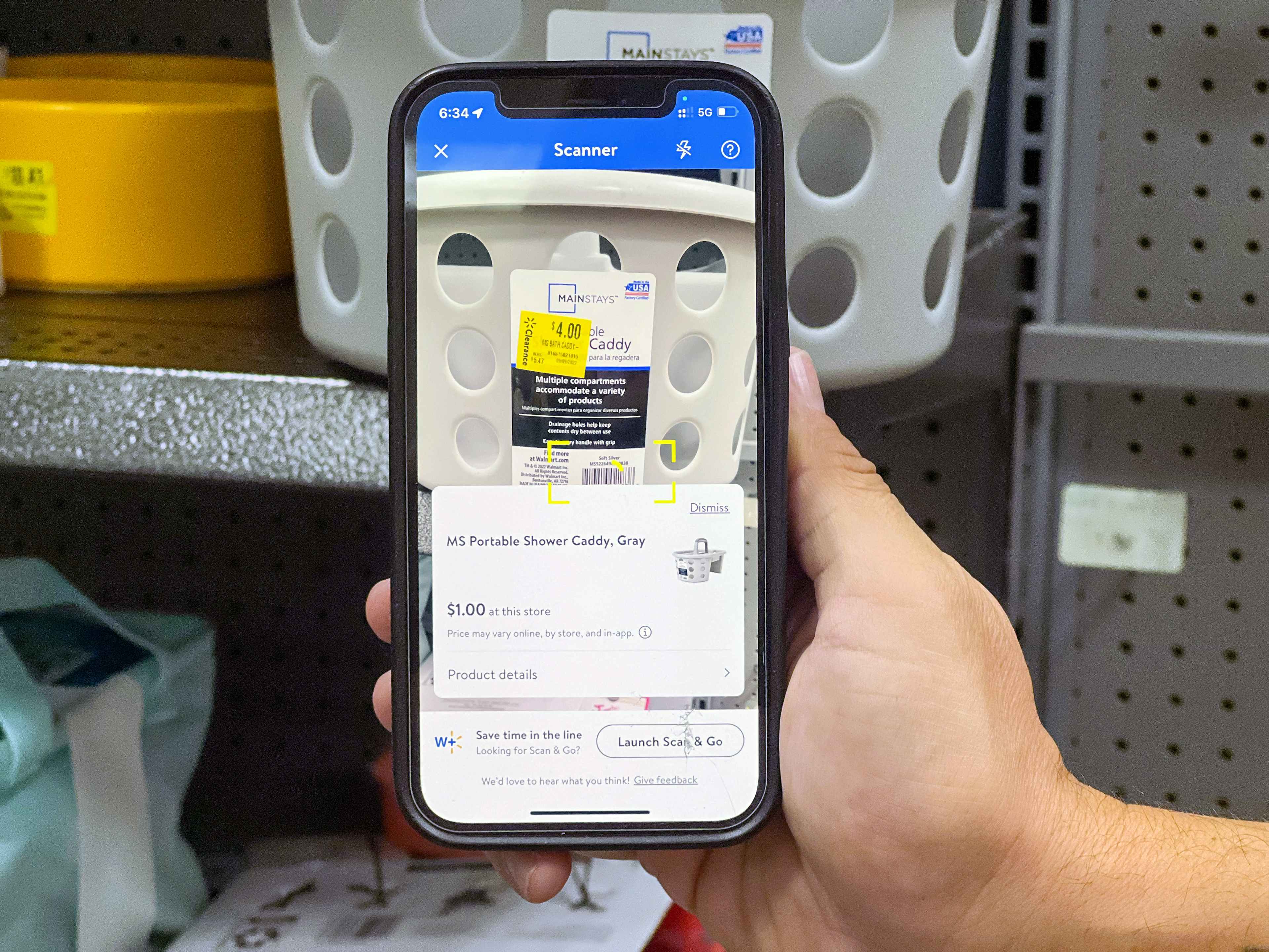Someone holding a phone, scanning a clearance item in the Walmart app which shows that although the sticker says the item is $4, it is ac...
