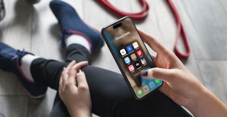 best fitness apps - A person looking at Fitness apps on a phone while on the floor of a gym