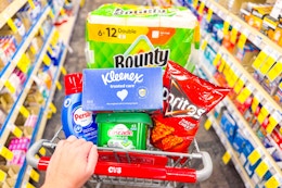 person pushing a cart with bounty, kleenex, cascade, persil, and doritos in it