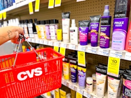 hand holding shopping basket next to shelf with John Frieda products