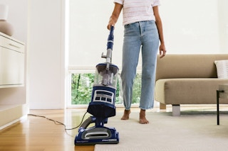 A person pushes a Shark Navigator Deluxe Vacuum NV360 toward the camera.