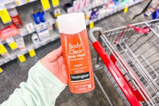 person holding a bottle of neutrogena body wash by a cart