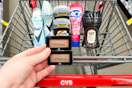 person holding maybelline eyeshadow over a cart with degree deodorant, axe deodorant, act toothpaste, and downy unstoppables