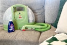 a Bissell Little Green carpet cleaner and cleaning solution on a sofa 