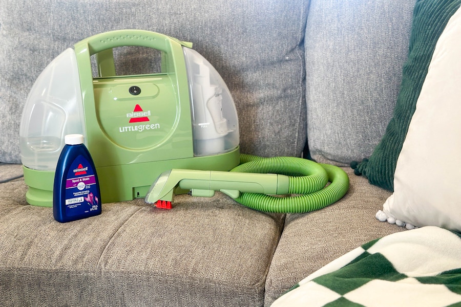 a Bissell Little Green carpet cleaner and cleaning solution on a sofa