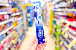 hand holding an oral-b essential clean toothbrush