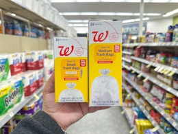 hand holding two walgreens brand trash bag packs