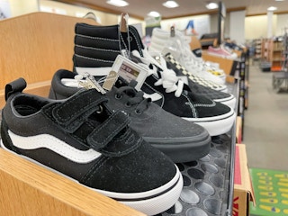 A variety of Vans shoes sitting on a display shelf.