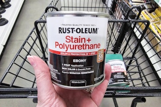 person holding a can of rustoleum stain and polyurethane over a shopping cart