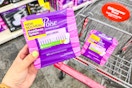 person holding a package of poise pads over a cart