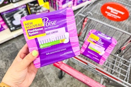 person holding a package of poise pads over a cart