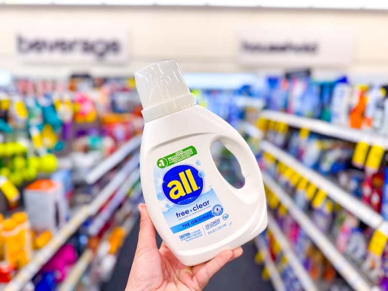 person holding a bottle of all laundry detergent in an aisle