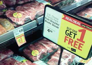 A Buy One Get One promotion sign in a store's meat section.