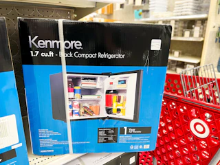 kenmore mini fridge sitting on a target shelf in front of a parked cart
