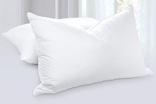 Two white pillows sit on a white bed, fluffy and filled with goose down.