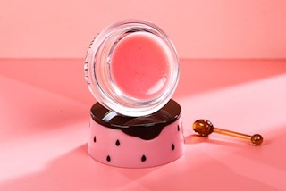 a strawberry lip mask on a pink surface