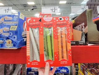 hand holding a bag of halloween decorated pretzel rods, mummies, fingers, and monsters