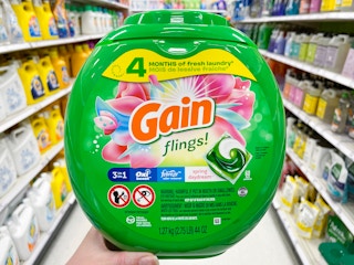 hand holding a tub of gain flings laundry detergent