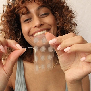 A woman peeling Dots for Spots acne patches from a sheet.