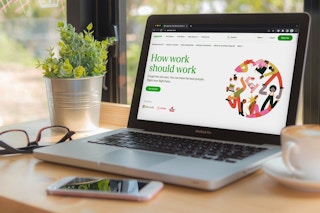 A laptop open on a desk displaying the Upwork website