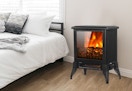 An electric fireplace next to a bed. 