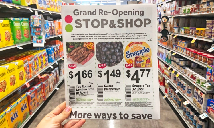 Hand holding Stop & Shop grand reopening ad in grocery store