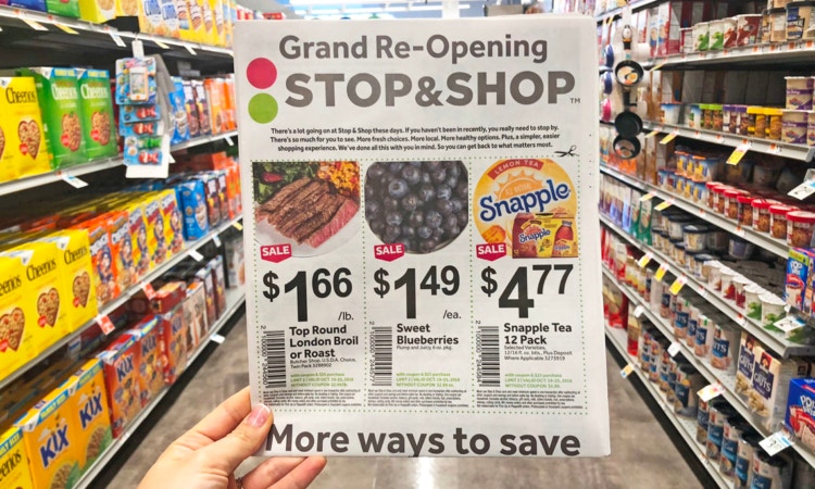 Hand holding Stop & Shop grand reopening ad in grocery store