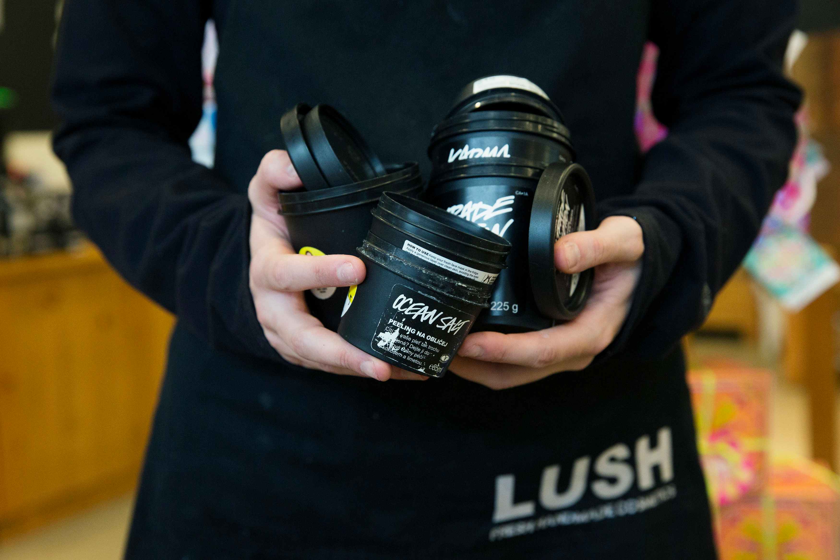 a lush employee holding a bunch of empty containers     