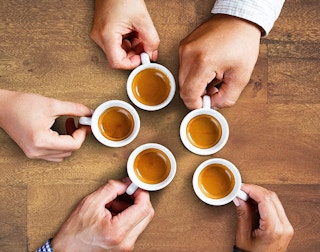 Hands holding espresso coffee cups on a table