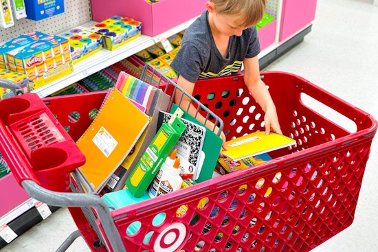 a child putting school supplies in a target cart 