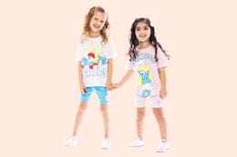 Two toddler girls holding hands wearing a Smurf lounge set (tee + bike shorts)