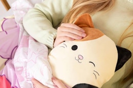 a girl holding a squishmallows heating pad