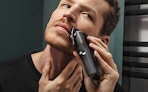 a person trimmer their beard with electric clippers