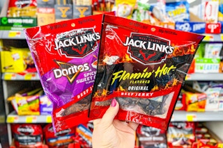 hand holding a bag of Jack Link's Flamin Hot and Doritos beef jerky in front of the snack area at Walmart