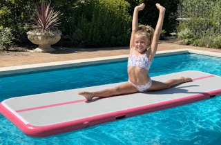 Lifestyle image of a girl using an inflatable gymnastics mat in the pool (created by banana studio)