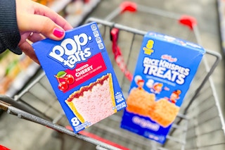 person placing a box of pop tarts in a cart with rice krispies treats