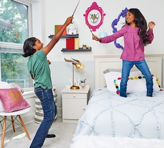 Two kids playing with wizard wands in a room