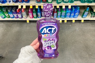 hand holding a bottle of act kids groovy grape mouthwash