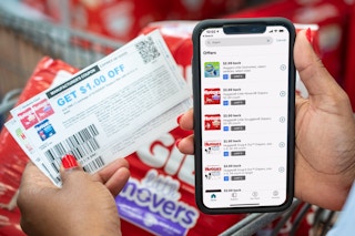 Ibotta app on a cell phone next to coupons and Huggies diapers.