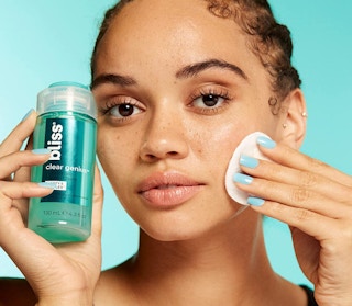 a woman putting toner on her face