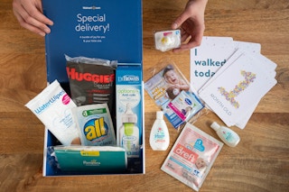 An open Walmart Registry baby welcome box with baby products inside and on the table next to it.