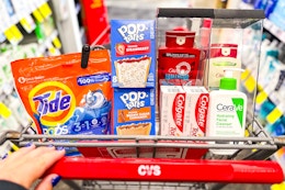 person pushing a cart with tide pods, pop-tarts, old spice body wash, colgate toothpaste, and cerave cleanser in it